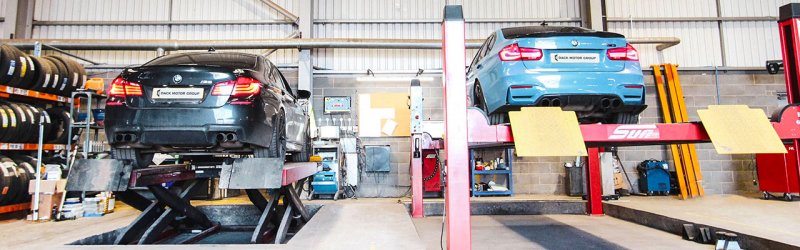 Photo of 2 BMW Cars on ramps in the workshop